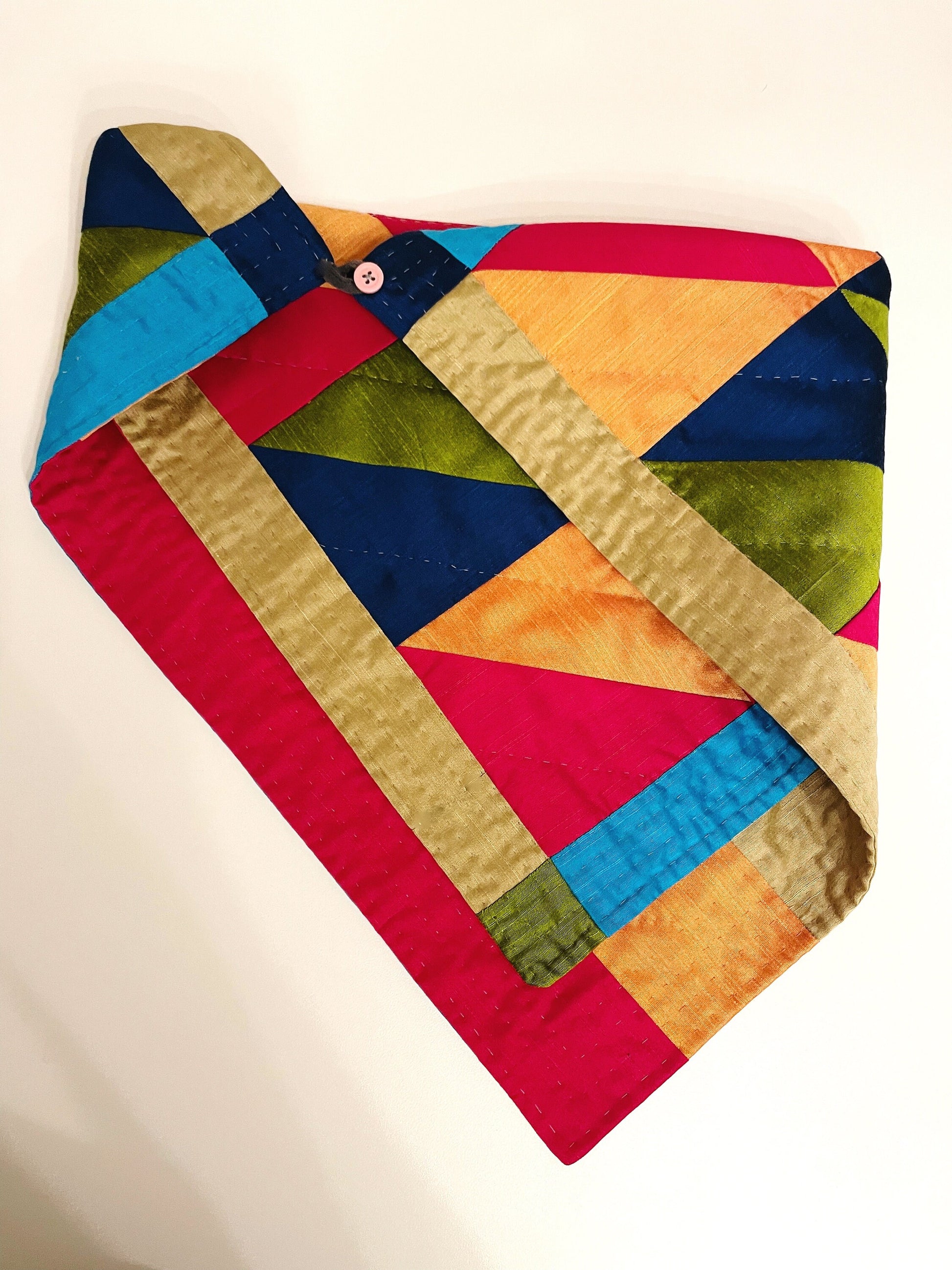 a quilted bandana lays folded and buttoned closed on a table. 