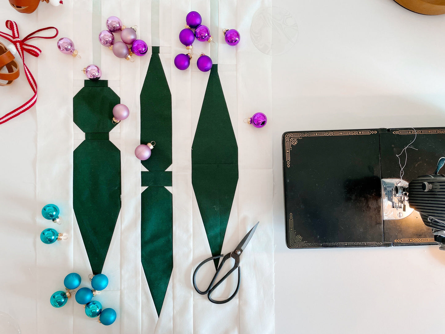 A quilt pattern laid out on a table with various colored beads and a pair of scissors, preparing for sewing.
