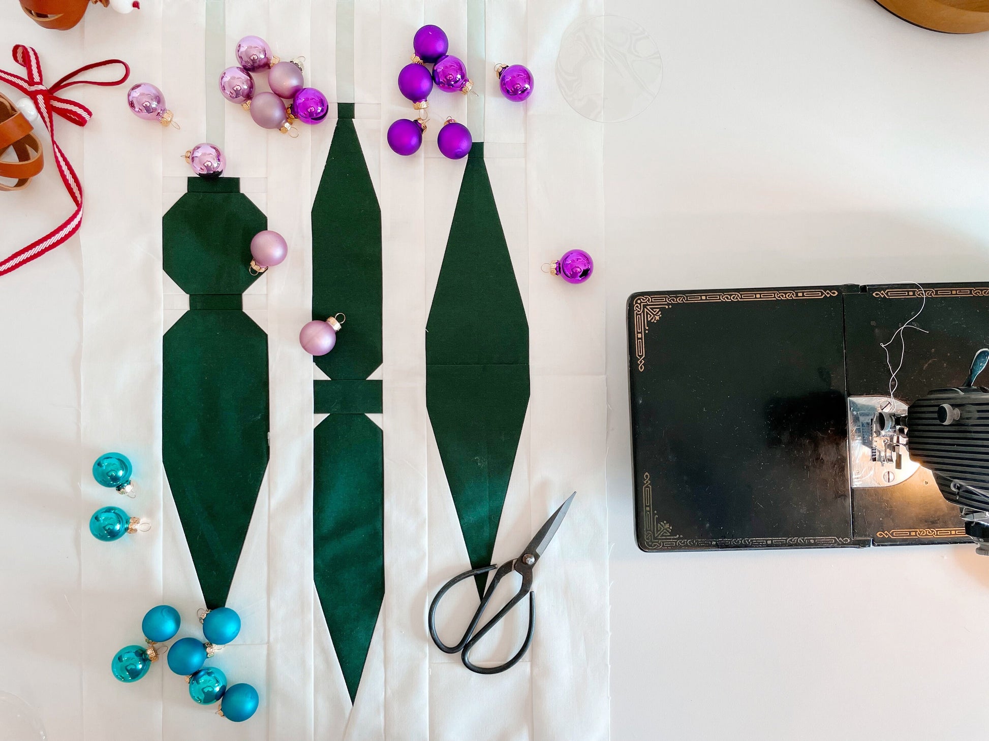 A quilt pattern laid out on a table with various colored beads and a pair of scissors, preparing for sewing.