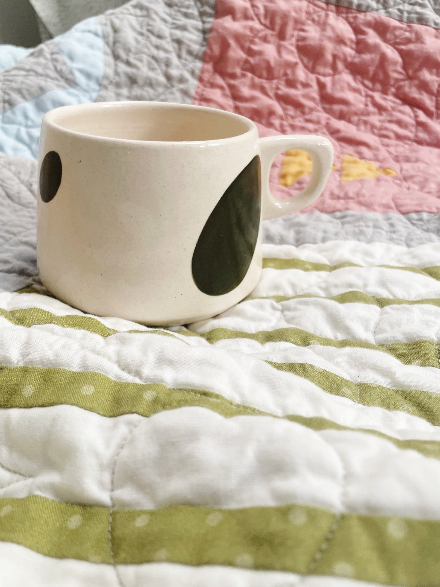 White mug with black circular design on a quilted surface