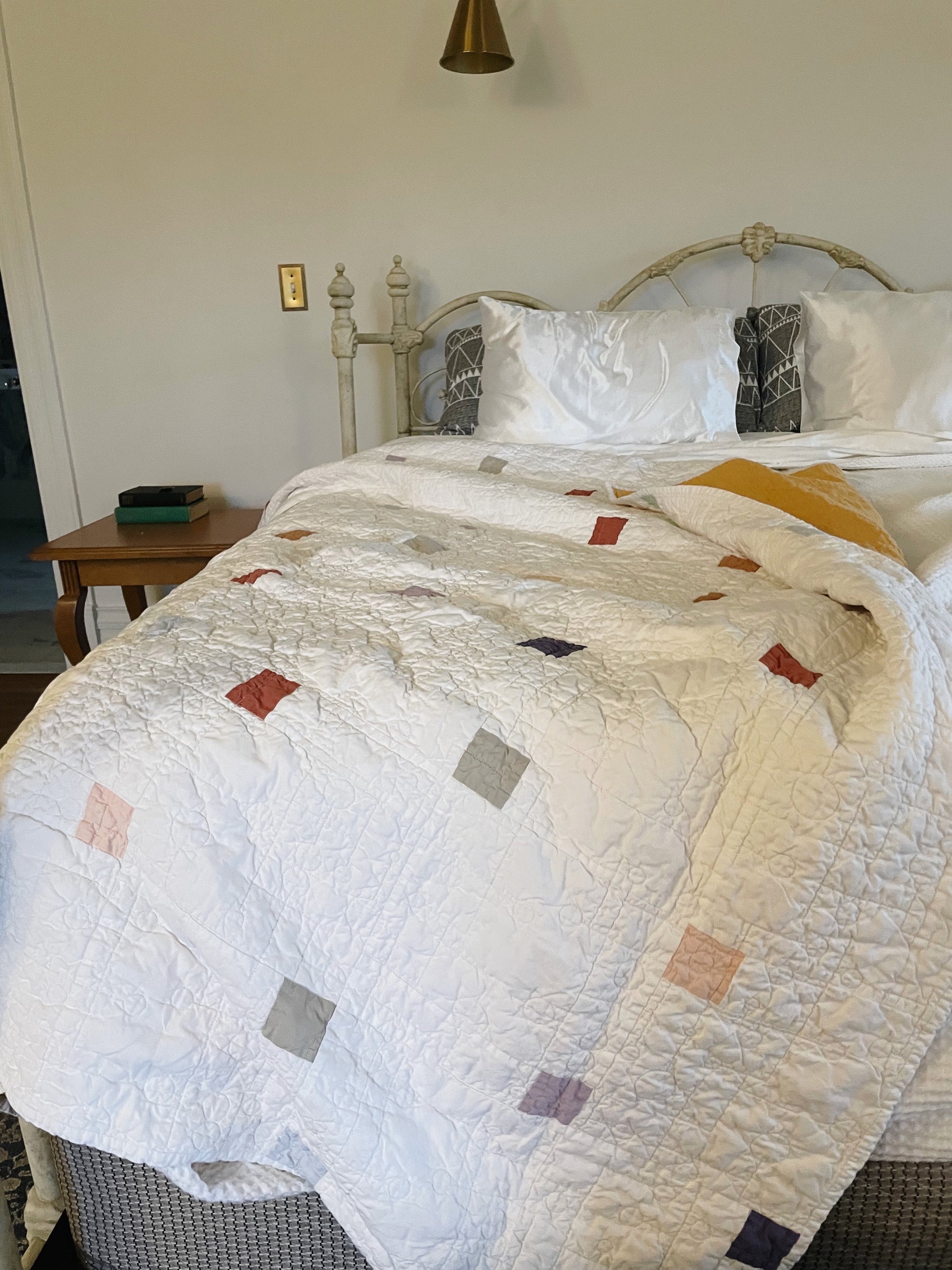 Bed with a quilt featuring square patterns in a bedroom setting