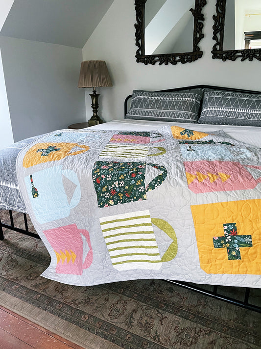 Colorful quilt with mug designs on a bed in a bedroom setting