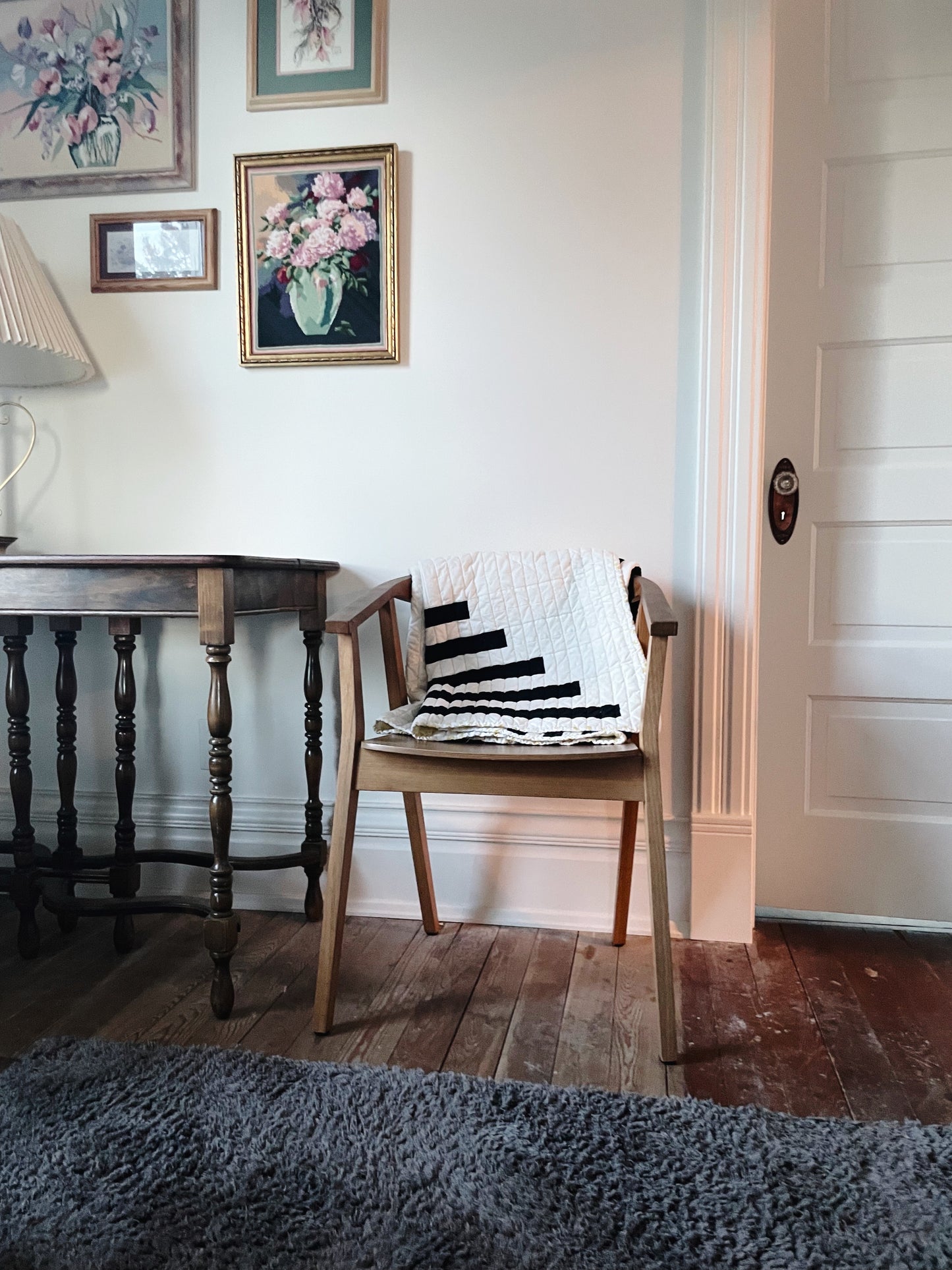 Chair with a striped cushion in a room with a table and framed pictures on the wall.
