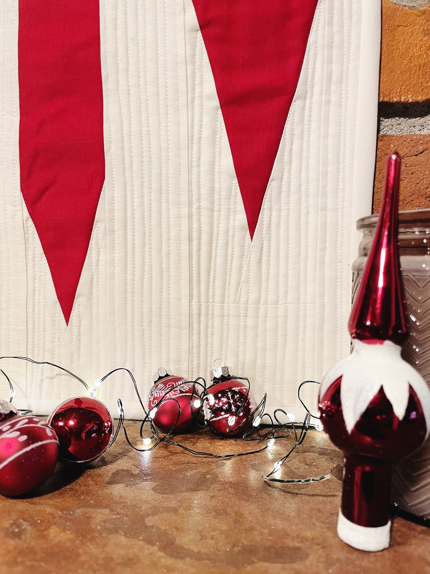 Close up of quilting with red christmas ornaments laying in front