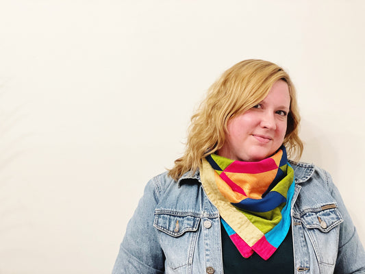 A person wearing a multicolored quilted bandana with a geometric pattern, standing in front of a white background.